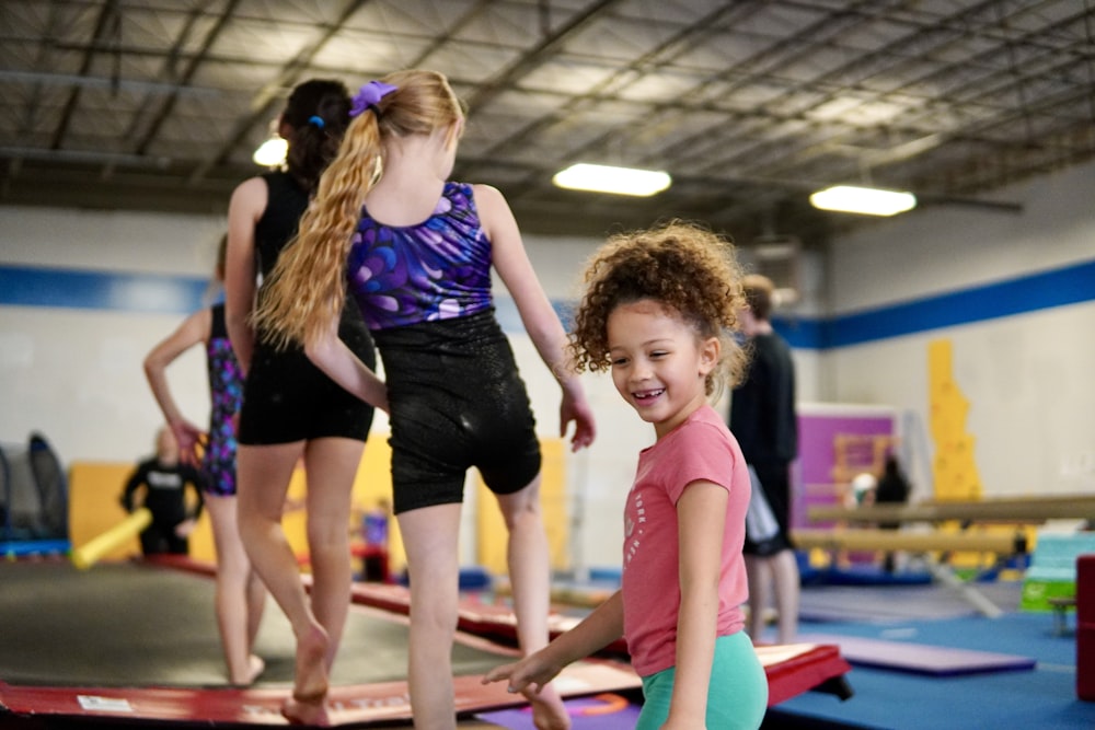Children practicing foundational gymnastics, balance, and tumbling movements in an indoor gym